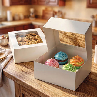 White bakery boxes with clear windows holding cupcakes and chocolate chip cookies