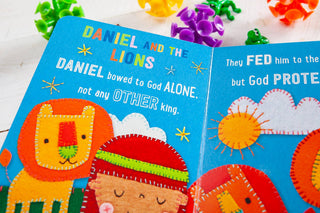 My First Bible Stories open board book showing Daniel and the lions with hand-stitched orange felt lion on blue pages