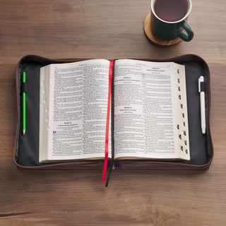 Brown zippered Bible cover open with Bible inside, pencils, and coffee mug nearby