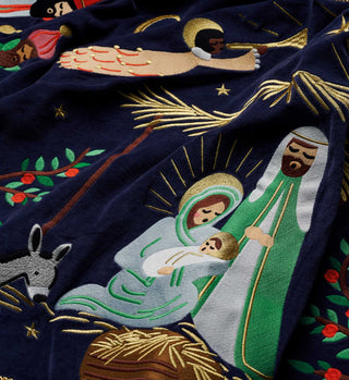 Close-up detail of embroidered nativity scene on navy blue velvet tree skirt