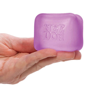 Lavender frosted NeeDoh squishy cube with internal speckles held horizontally for scale