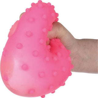 Hand squeezing bright pink textured stress ball with raised bumps on white background