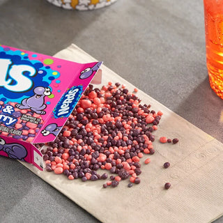 Nerds candy strawberry and grape flavors spilling from pink box onto napkin