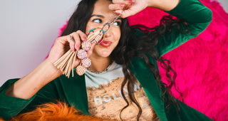 Model holding Consuela Vanessa Charm featuring woven leather knot beads and tassel detail.