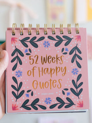 Hand holding pink spiral-bound 52 Weeks of Happy Quotes desk flip calendar by Pippi Post