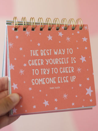 Spiral-bound desk flip calendar with Mark Twain motivational quote on coral background with stars
