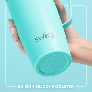 Turquoise Swig tumbler with built-in silicone coaster held by a hand on a light blue background
