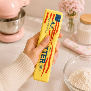 Squeezing yellow butter stick squishy toy showing slow rise elasticity in pink kitchen scene