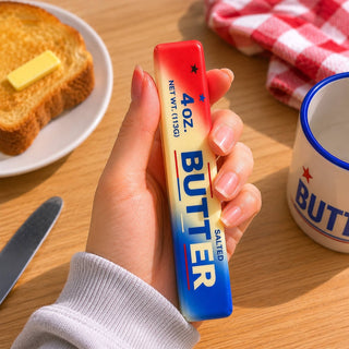 Hand holding red white blue gradient butter squishy next to toasted bread in kitchen setting