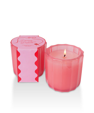 Aromatique Peony Petals ribbed pink glass candle lit beside its decorative pink and red packaging box