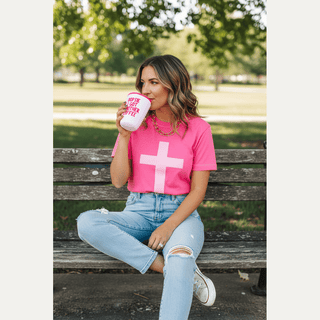Pink Cross Puff Tee worn with high-waisted jeans sitting on park bench with coffee
