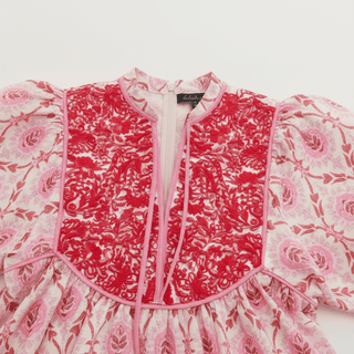 Pink floral embroidery detail on white cotton mini dress with puff sleeves and piping trim