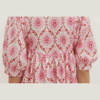 Back view of pink botanical print mini dress showing gathered waist and tiered skirt silhouette