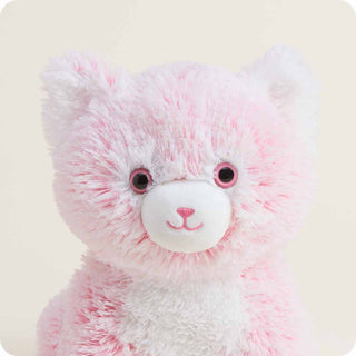 Close-up of a pink and white fluffy plush kitten stuffed animal with embroidered smile