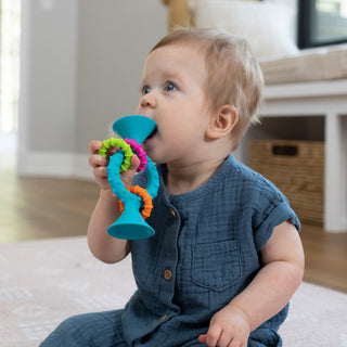 Baby chewing on Fat Brain Toys PipSquigz Loops teething toy in teal with colorful rings