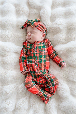Sleeping newborn wearing Caden Lane red and green plaid Christmas zipper footie with matching headband bow