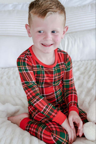 Young boy smiling in red and green plaid Christmas two-piece bamboo pajama set