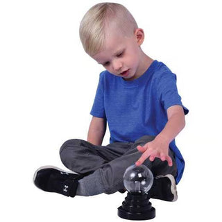 Young child touching a small plasma light ball with black base