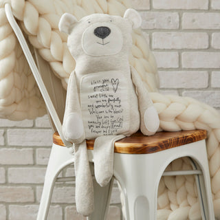 Light gray plush bear with inspirational message on tummy seated on wooden chair