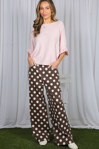Brown wide-leg denim pants with large white polka dots, paired with pink knit top