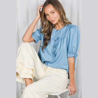 Seated model wearing light blue polka dot shirt with cream wide-leg pants