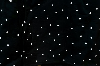 Black fabric with scattered white polka dot print pattern close-up detail