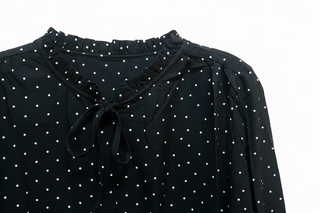 Black polka dot long sleeve blouse with ruffle neckline and front tie detail