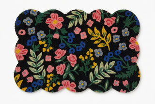 Black scallop-edged rug with colorful floral pattern in pink, blue, and yellow