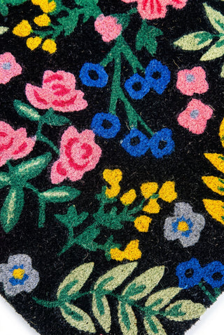 Black oval wool rug with colorful embroidered floral pattern in pink, blue, and yellow