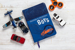 Blue leatherette Prayers & Promises for Boys devotional book surrounded by toy cars, airplane, and fidget spinner