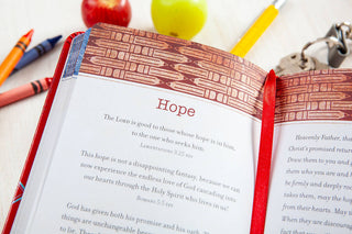 Open red devotional book showing Hope page with Bible verses, beside apples and crayons