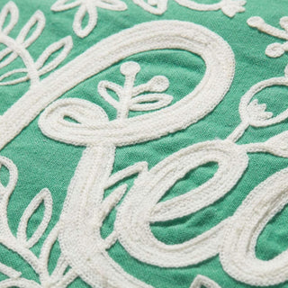 Close-up detail of white chain-stitch embroidery on green cotton pillow cover with floral motifs