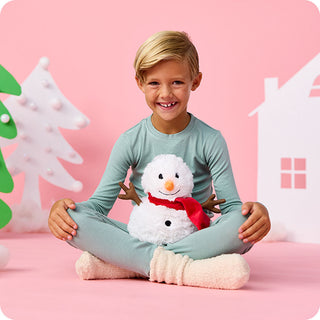 Child holding a white plush snowman with red scarf Warmies stuffed animal toy