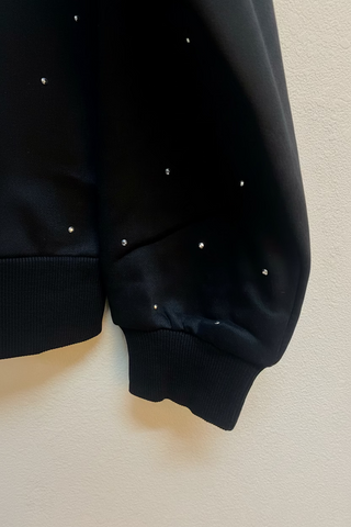Black sweatshirt sleeve with scattered silver rhinestone studs and ribbed cuff