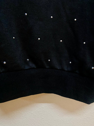 Black sweatshirt hem detail with scattered silver rhinestone studs and ribbed band