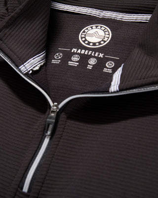Close-up detail of Flag & Anthem MadeFlex black quarter-zip mock neck interior label and zipper