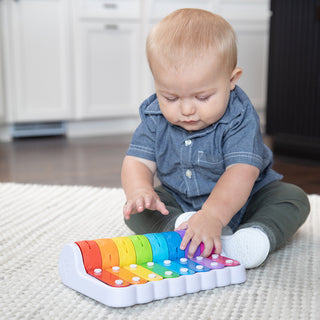 Baby playing with Fat Brain Toys Rock N Roller Piano rainbow musical toy on carpet