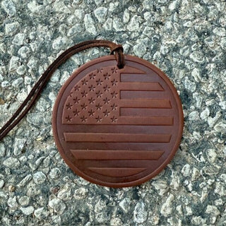 Round brown leather ornament with embossed American flag design on a cord