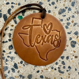 Round tan leather ornament engraved with Texas state outline and script lettering