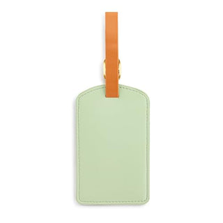 Sage green leather luggage tag with orange strap and gold metal hardware on white background