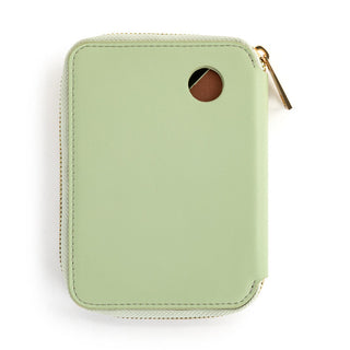 Back view of a sage green zip-around passport wallet with gold zipper and circular cutout window