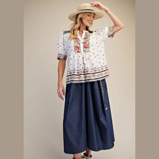 Woman wearing a patterned blouse and navy skirt 