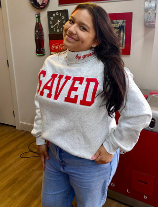 Gray mock neck sweatshirt with bold red SAVED lettering and by grace collar text