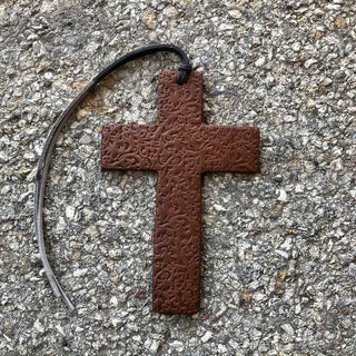 Brown vegetable-tanned leather scroll cross car air freshener with embossed texture and black loop
