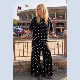 Black scuba polka dot short sleeve set with drop shoulders and wide-leg pants on stadium balcony