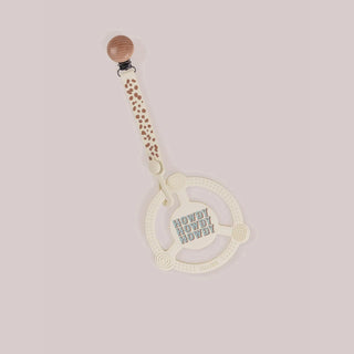 Off-white silicone teether ring with raised dots spiral and ribbed textures, embossed Howdy text, cream polka dot strap, and wood clip