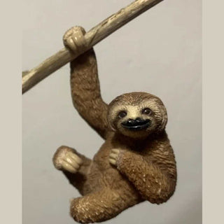 Sloth figurine hanging from a branch 