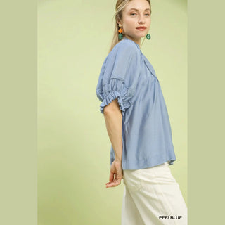Woman wearing a light blue blouse with ruffled sleeves 