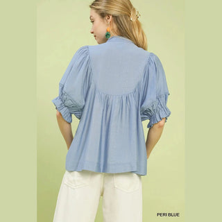 Woman wearing a light blue blouse with ruffled sleeves 