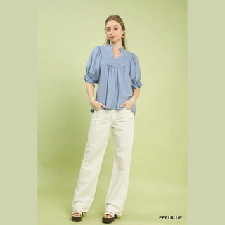Woman wearing a blue blouse and white pants 